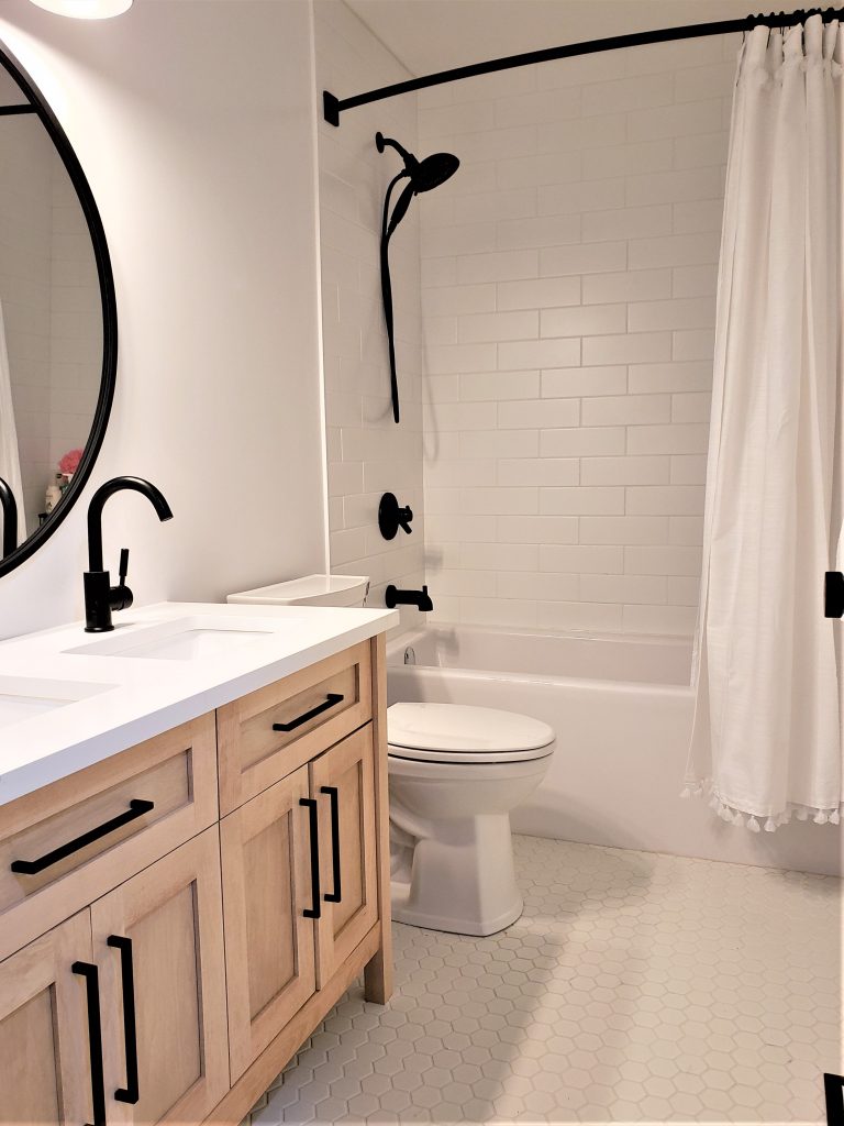 white bathroom with subway tile, black trim and wood vanity